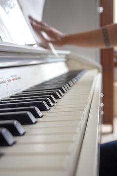 Woman practicing lessons on her white electric piano