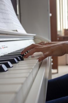 Woman practicing lessons on her white electric piano