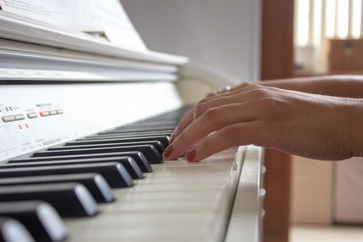 Woman practicing lessons on her white electric piano