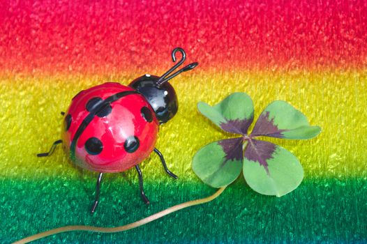 The picture shows lucky clover and a ladybird on colorful crepe paper