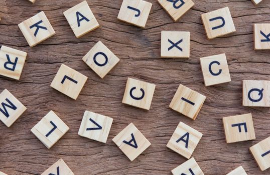 background of letterpress wood type printing blocks on wooden background, random letters of alphabet and punctuation stained by black inks
