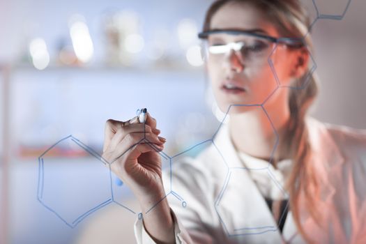 Portrait of a confident female health care expert in life science laboratory writing structural chemical formula on a glass board. Healthcare and modern life science concept. Blue toned image.