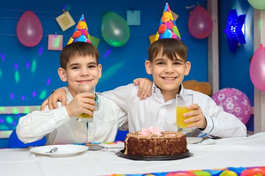 Two boys eat cake and drink juice at a birthday party