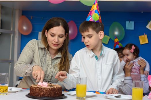Mother and son cut a cake in honor of the birthday