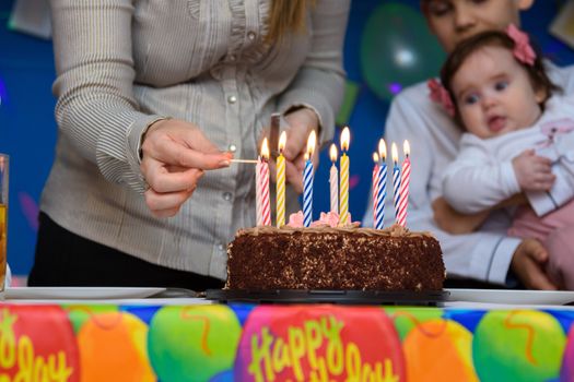 Mom lights candles on a cake at a birthday party