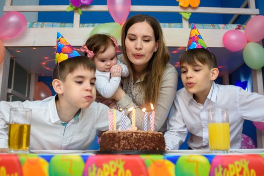 Family blowing candles on birthday cake