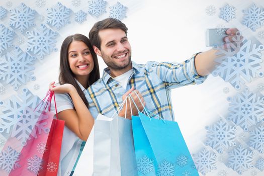 Attractive young couple with shopping bags taking a selfie against snowflake frame