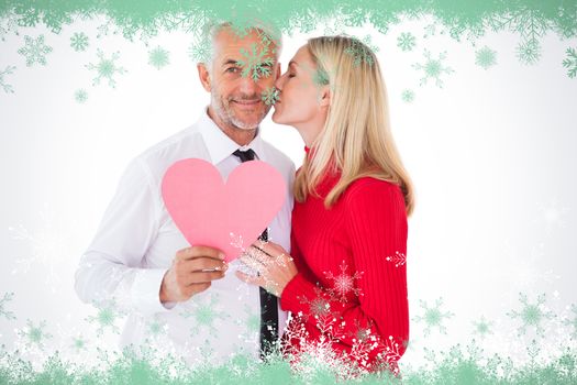Handsome man holding paper heart getting a kiss from wife against snow flake frame in green