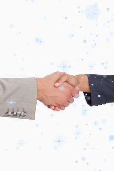 Side view of shaking hands of business people against snow falling