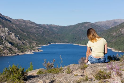 Young happy woman at the mountain, relaxing and enjoying the lake at Geres, Portuguese National Park