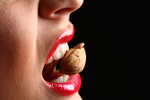 woman red lips eating tasty food. Woman cracking a nut with her white teeth