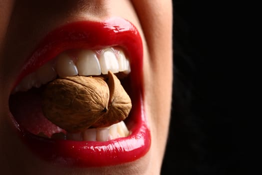 woman red lips eating tasty food. Woman cracking a nut with her white teeth