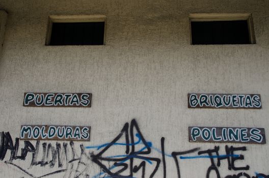 Products advertised for sale and grafitti in a wall. Puerto Montt. Los Lagos Region. Chile.