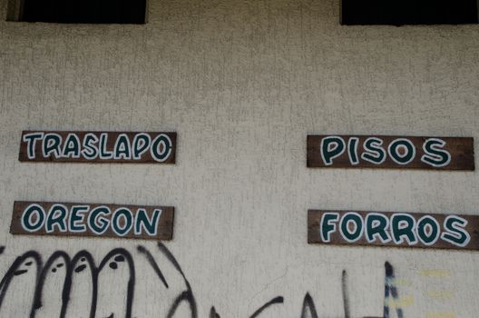 Products advertised for sale and grafitti in a wall. Puerto Montt. Los Lagos Region. Chile.