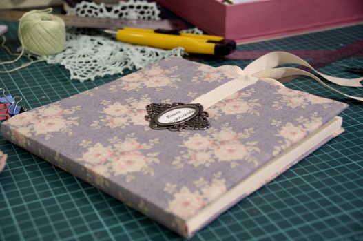 the process of handmade creating of the diary from special scrapbooking paper, paper flowers and other decorative elements