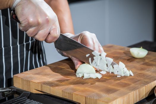 Chef cutting the onions on a wooden board