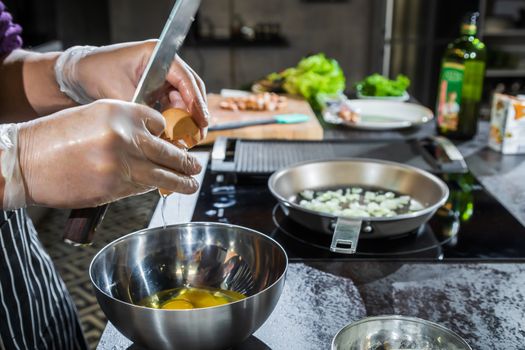 Cook cook an omelet with onions and sausages in a pan