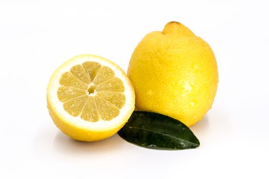 Ripe lemon and slices with green leaves on white background.