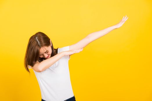 Asian happy portrait beautiful cute young woman teen smile standing wear t-shirt move showing DAB dance against gesture isolated, studio shot on yellow background with copy space