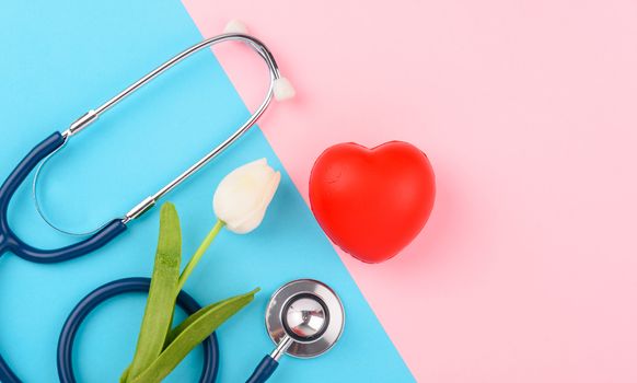 Doctor's Day concept, flat lay top view, stethoscope with red heart on pink blue background, diagnosis of heart disease with copy space for text