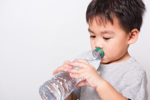 Closeup Asian face, Little children boy drinking water from Plastic bottle on white background with copy space, health medical care