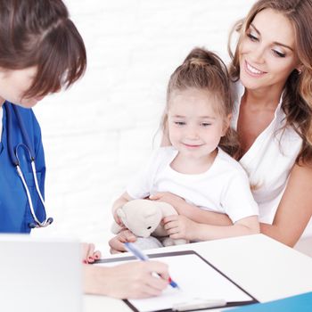 Pediatrician doctor writing prescription to girl and her mother