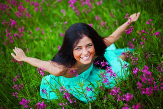 Beautiful young woman in dress on summer flower field
