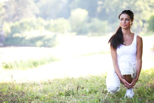 Runner woman stretching thigh ready to running in forest park in summer morning, female fitness model in white