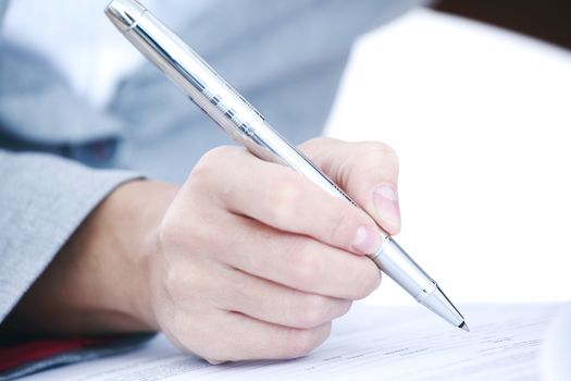 Business woman in suit signing contract with pen, document, paperwork