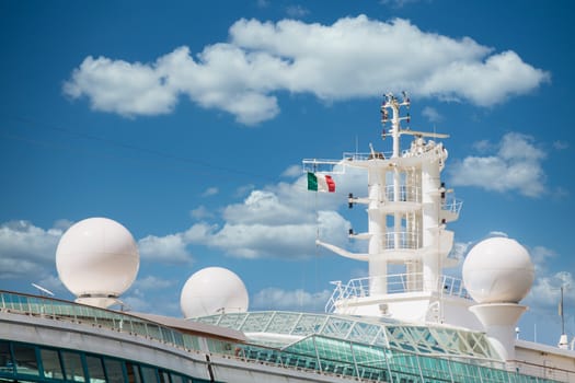 Satellite and Communication equipment on a cruise ship under blue skies and an Italian flag