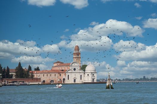 A boat speeding across Grand Canal in Venice toward old church