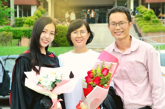 Asian university student and family celebrating graduation outdoor