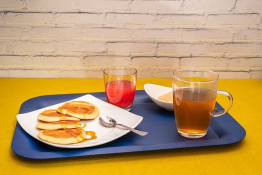 Breakfast with maple syrup pancakes, hot tea and blood orange juice
