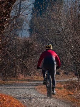 Rear view of a cyclist riding his mountain bike on a path in nature, street photography