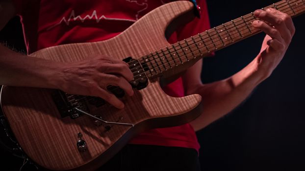 detail of hand playing an electric guitar, color image