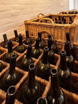 Empty dark glass bottles ready for bottling wine arranged in wicker baskets