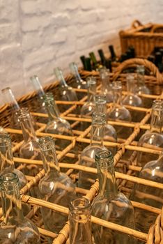 Empty clear glass bottles ready for bottling wine placed in wicker baskets