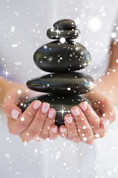 Beauty therapist holding pile of stones for massage against snow falling