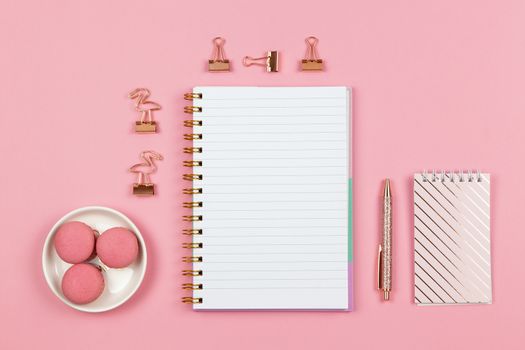 Modern female working space, top view. Notebooks, pen, clamps on pink backround, copy space, flat lay. Desktop of freelancer, student. Work from home, back to school, education concept. Horizontal.
