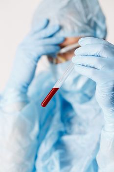 Close up of doctor hand holding blood sample. Medical equipment. Blood test. A doctor wearing personal protective equipment including mask, goggle, and suit to protect COVID 19 coronavirus infection.