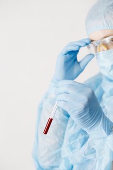 Close up of doctor hand holding blood sample. Medical equipment. Blood test. A doctor wearing personal protective equipment including mask, goggle, and suit to protect COVID 19 coronavirus infection.