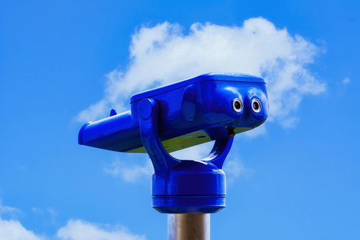 A pair of coin-operated binoculars against blue sky