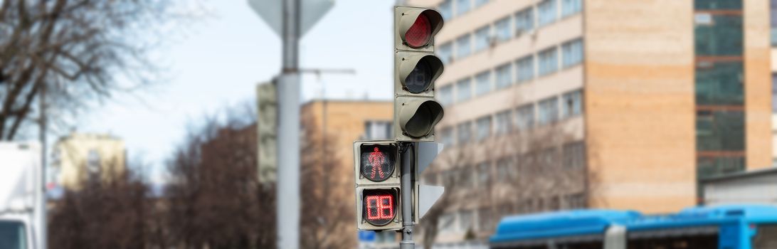 The traffic light shows red, which prohibits traffic for people. Caution sign. Blurred background of the street and the light of day.