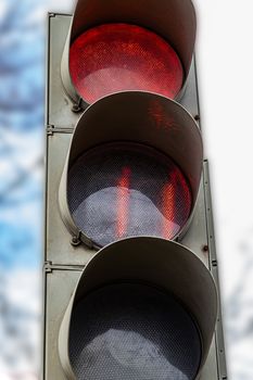 The traffic light shows red, which prohibits traffic for people. Caution sign. Blurred background of the street and the light of day.