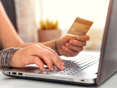 Online shopping concept. Close-up woman's hands holding credit card and using laptop keyboard for online shopping