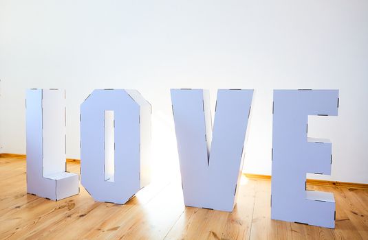 3D Standing Letters forming word LOVE from white cardboard on a light background. Relationship concept