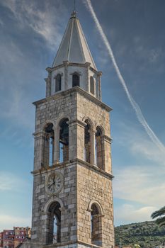 A clock tower on an old stone tower in Dubrovnik, Croatia under blue sky