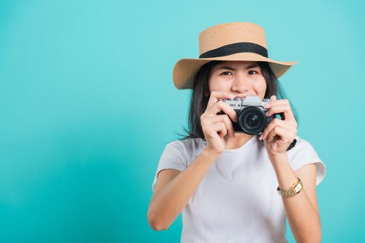 Traveler tourist happy Asian beautiful young woman smile in summer hat standing with mirrorless photo camera, shoot photo in studio on blue background with copy space for text