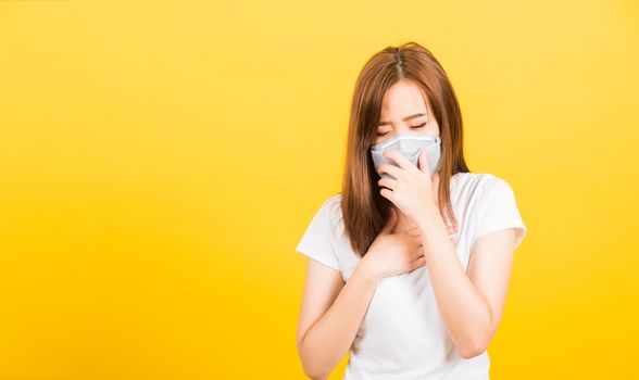 Asian happy portrait beautiful cute young woman teen standing wear t-shirt cough in mask protection from virus epidemic or air pollution isolated, studio shot on yellow background with copy space