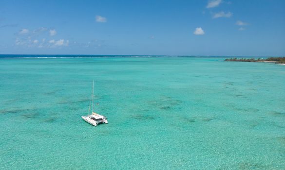 Catamaran sailing boat in turquoise sea lagoon on tropial Mauritius island. Aerial, top down drone view.